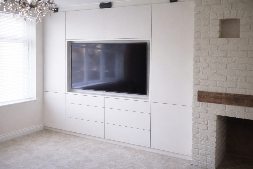 Bespoke built-in TV wall with handleless storage cabinets in a modern living room in Good Easter, Essex