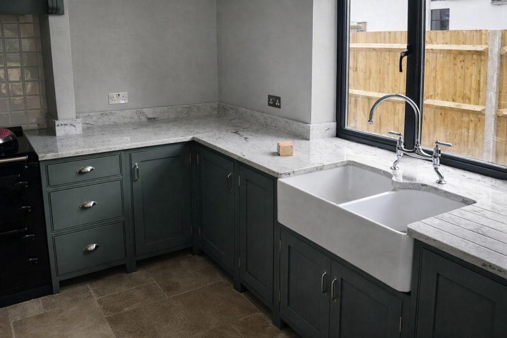 Full view of a bespoke shaker-style kitchen painted in Farrow & Ball Green Smoke with custom cabinetry and integrated AGA.