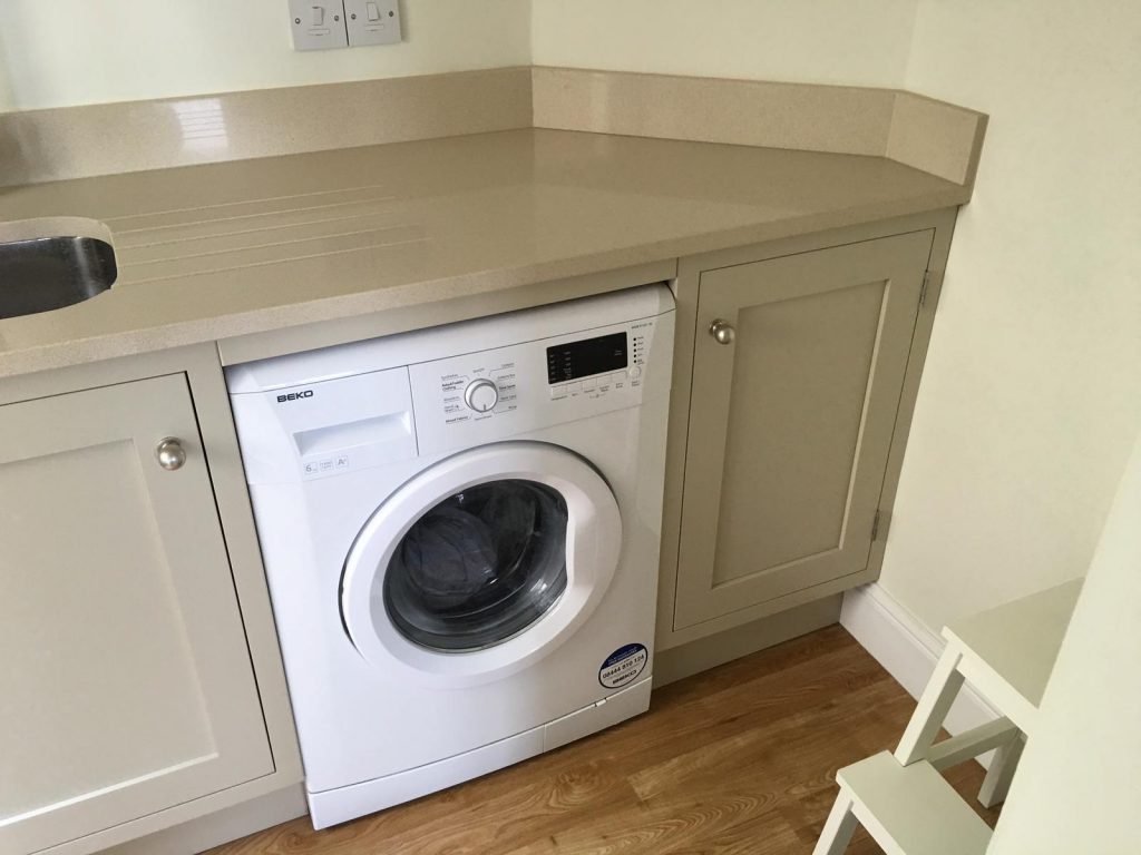 Bespoke shaker-style utility room cabinetry in Barnstead, featuring an integrated washing machine fitted beneath a solid worktop