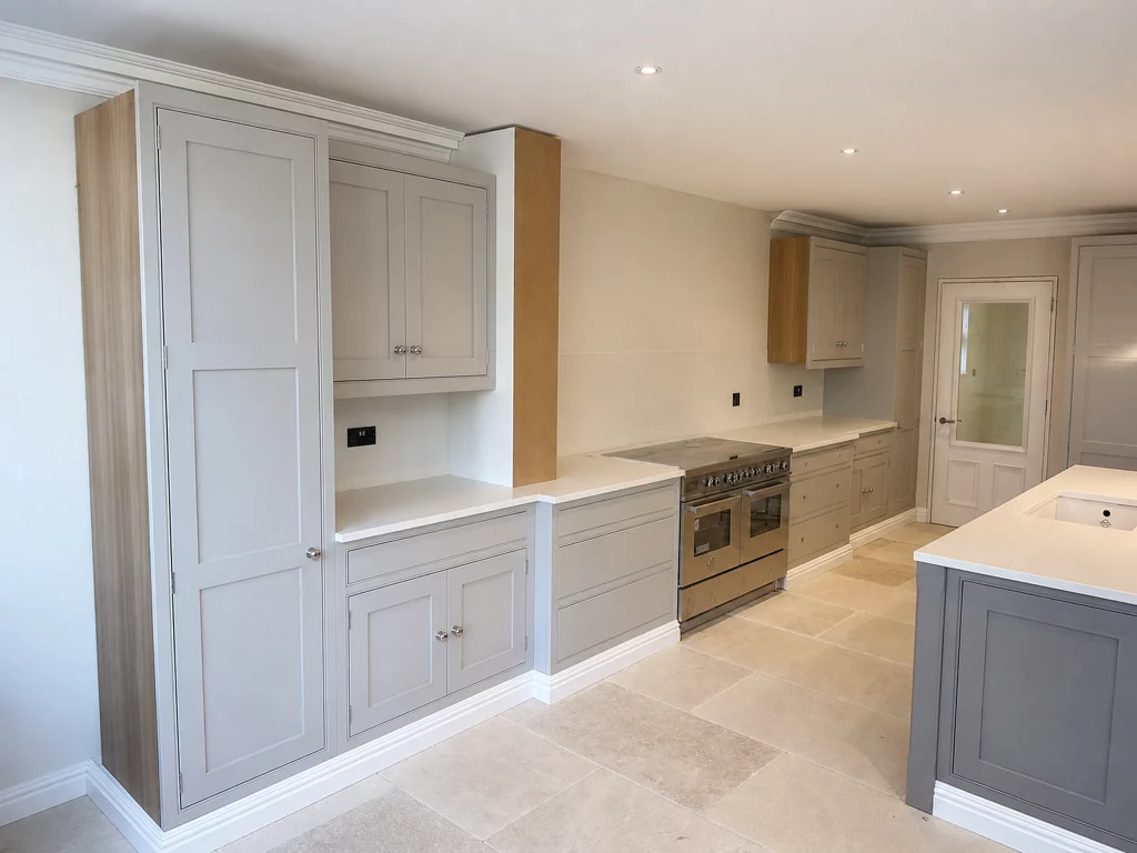 Grey in-frame kitchen installation with oak interiors and white quartz worktops in Braintree, painted wall cabinetry and island viewed from the doorway.