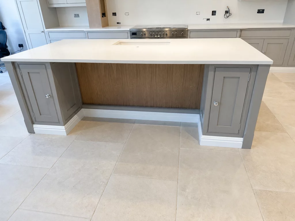 Grey in-frame kitchen installation with oak interiors and white quartz worktops in Braintree, island rear elevation awaiting final fitting.