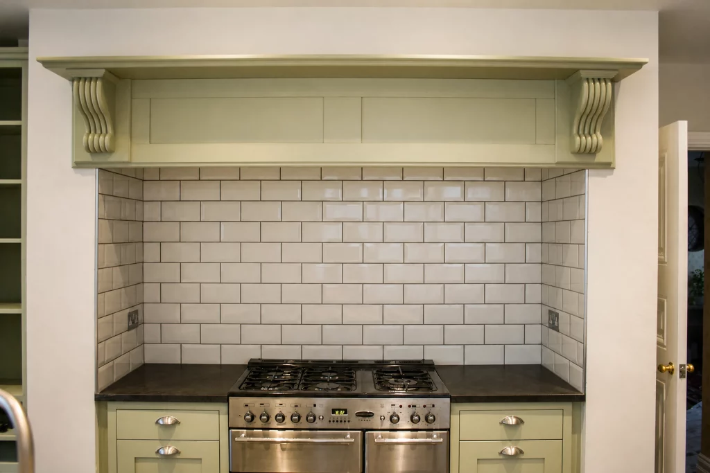 Cooking Apple Green Shaker kitchen with oak worktops and a tiled range recess, front view of the freestanding range within its tiled recess.