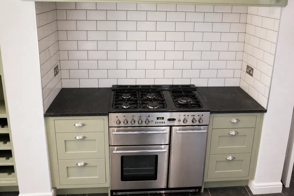 Cooking Apple Green Shaker kitchen with oak worktops and a tiled range recess, closer view of the range and granite worktop.