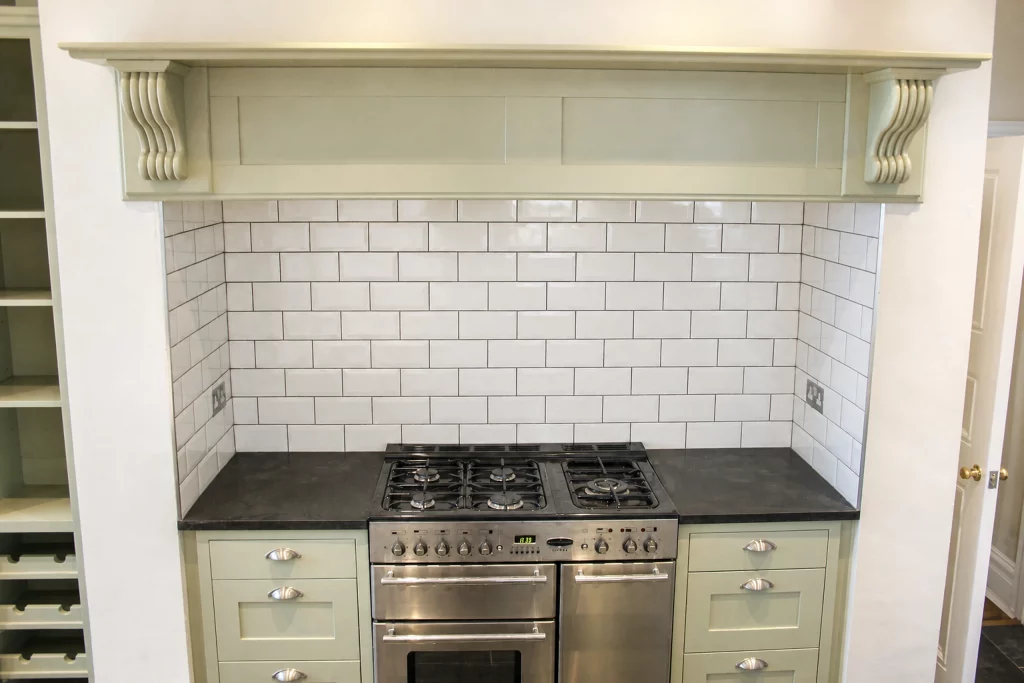 Cooking Apple Green Shaker kitchen with oak worktops and a tiled range recess, symmetrical range-cooker recess with painted overmantel.