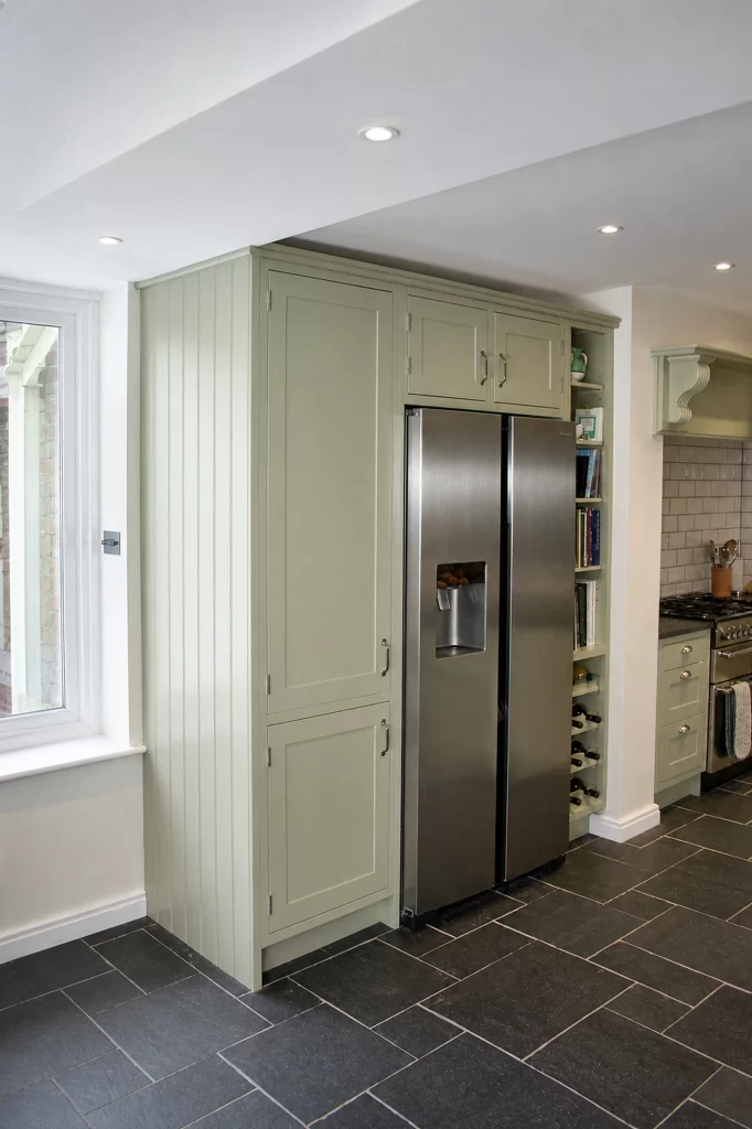 Cooking Apple Green Shaker kitchen with oak worktops and a tiled range recess, finished tall fridge housing and adjacent cabinetry.