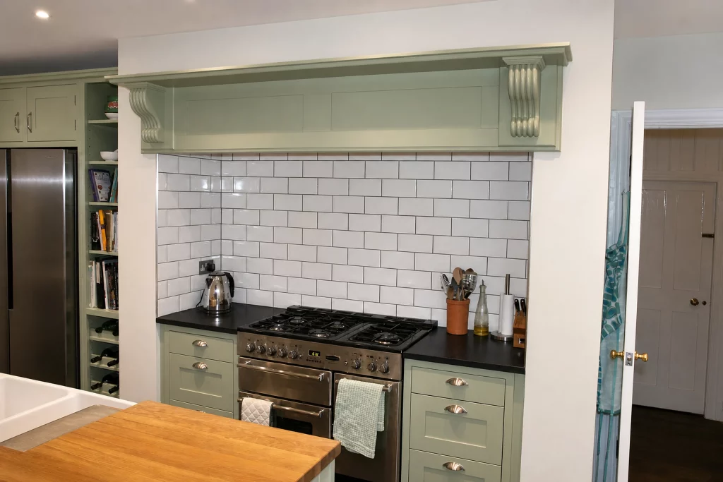 Cooking Apple Green Shaker kitchen with oak worktops and a tiled range recess, range recess framed by the island worktop.