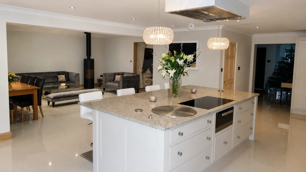 Dimpse-painted Shaker kitchen with a large granite island and integrated appliances, open-plan view showing the island and adjoining lounge.