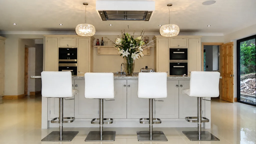 Dimpse-painted Shaker kitchen with a large granite island and integrated appliances, front elevation of the island with four seats.