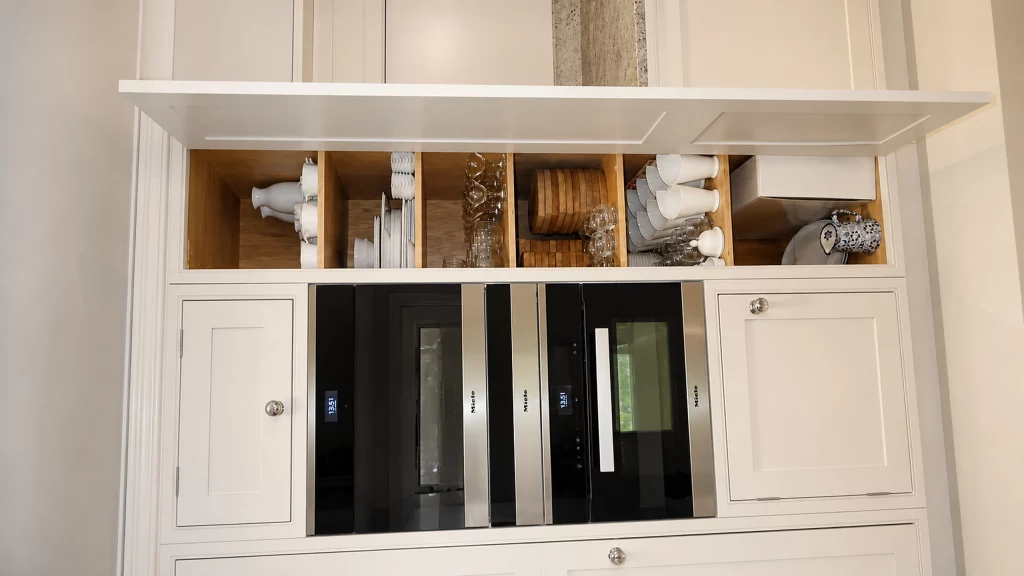 Dimpse-painted Shaker kitchen with a large granite island and integrated appliances, integrated wine storage concealed behind pocket doors.