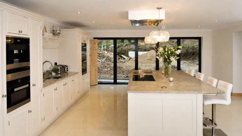 Dimpse-painted Shaker kitchen with a large granite island and integrated appliances, long perspective along the island and sink run.