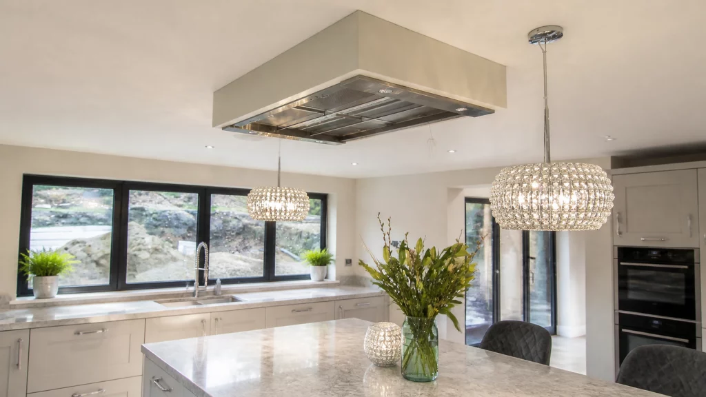 Dimpse-painted Shaker kitchen with a large granite island and integrated appliances, bespoke extractor canopy above the island.