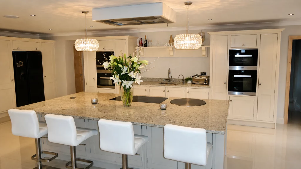 Dimpse-painted Shaker kitchen with a large granite island and integrated appliances, wide island view with pendant lights.