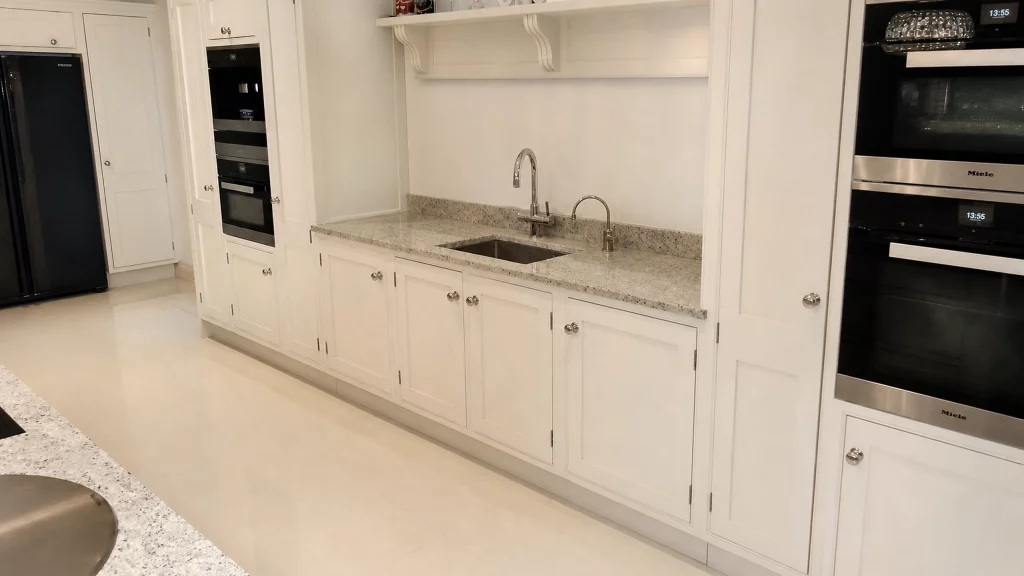 Dimpse-painted Shaker kitchen with a large granite island and integrated appliances, long painted sink run with integrated appliances.