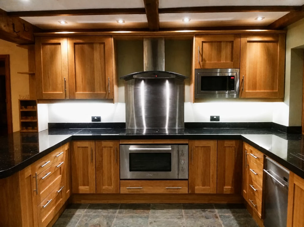 Handcrafted solid oak kitchen with dark stone worktops in a beamed interior, main cooking run with overhead task lighting.