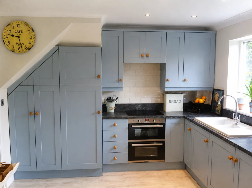 Parma Gray painted kitchen with dark worktops and made-to-measure storage, wide view showing tall storage fitted beneath the sloping ceiling.