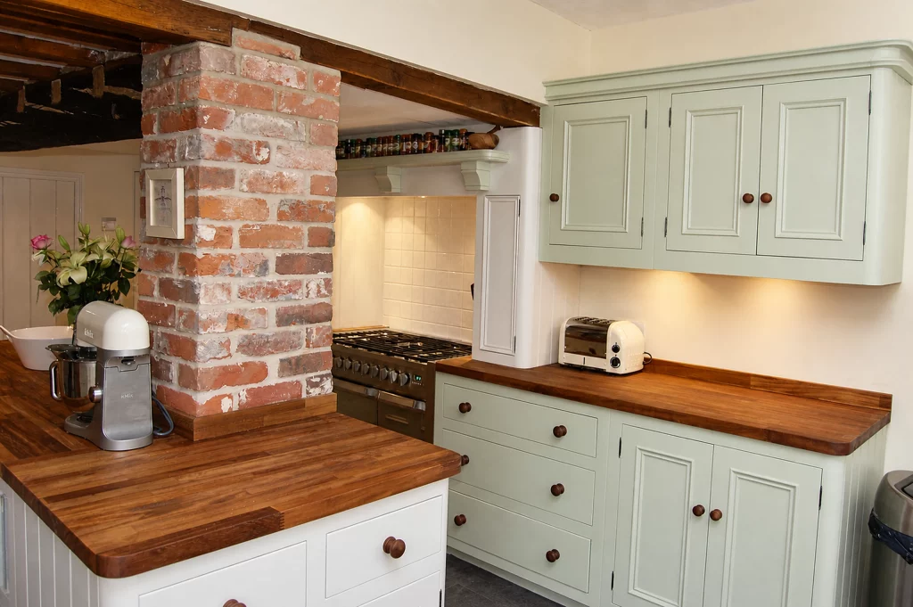 Painted country kitchen with replacement solid iroko worktops in Little Dunmow, iroko worktop shaped around an exposed brick pier.