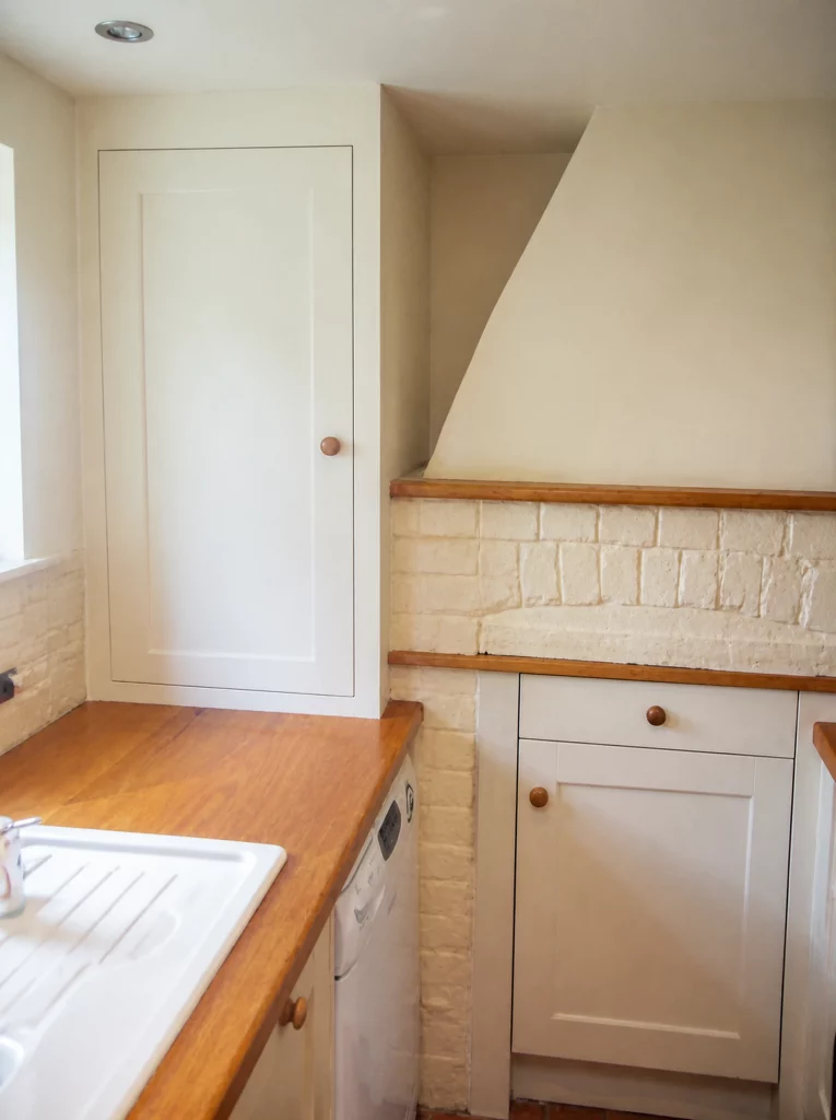 Compact painted Shaker kitchen with solid oak worktops in Little Waltham, full-height door beside the oak worktop.