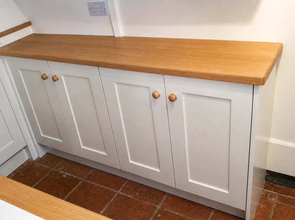 Compact painted Shaker kitchen with solid oak worktops in Little Waltham, long bank of Shaker base cabinets with timber knobs.