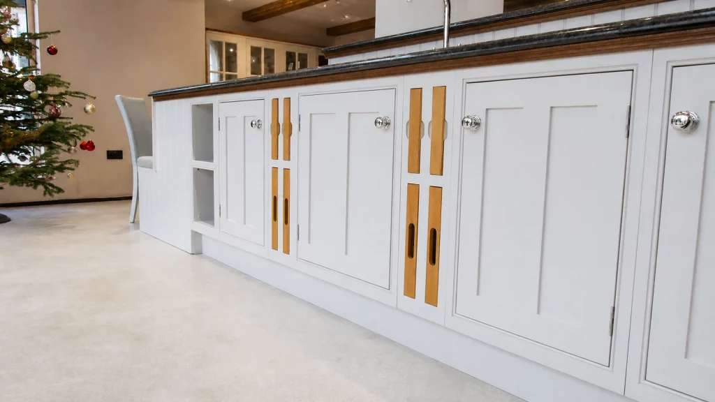 Painted pale-blue Shaker kitchen with dark granite worktops and oak details, close view of the peninsula cabinetry and oak inlay details.