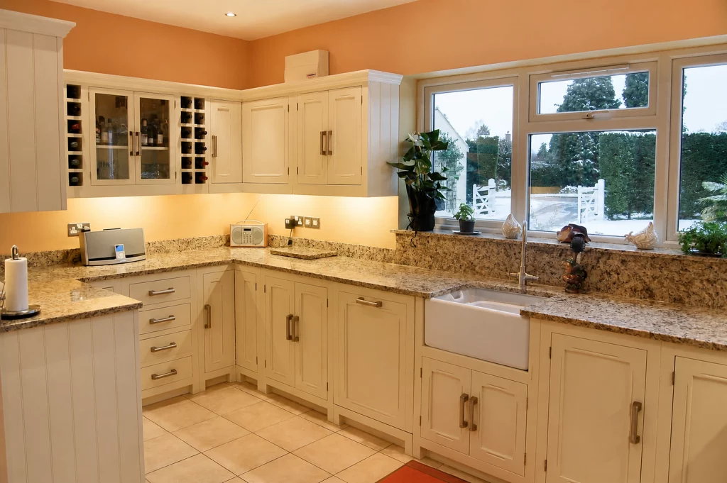 Tallow-painted in-frame Shaker kitchen with granite worktops and fitted wine storage, corner layout with glazed cupboards and integrated wine racks.