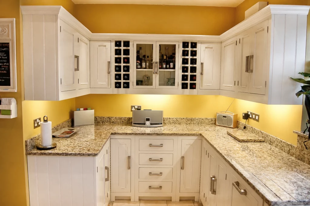Tallow-painted in-frame Shaker kitchen with granite worktops and fitted wine storage, granite preparation area and drawer bank.