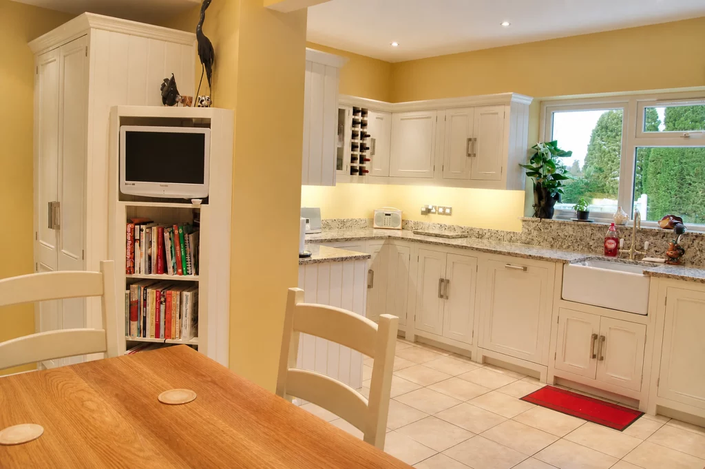 Tallow-painted in-frame Shaker kitchen with granite worktops and fitted wine storage, wide dining-area view into the fitted kitchen.