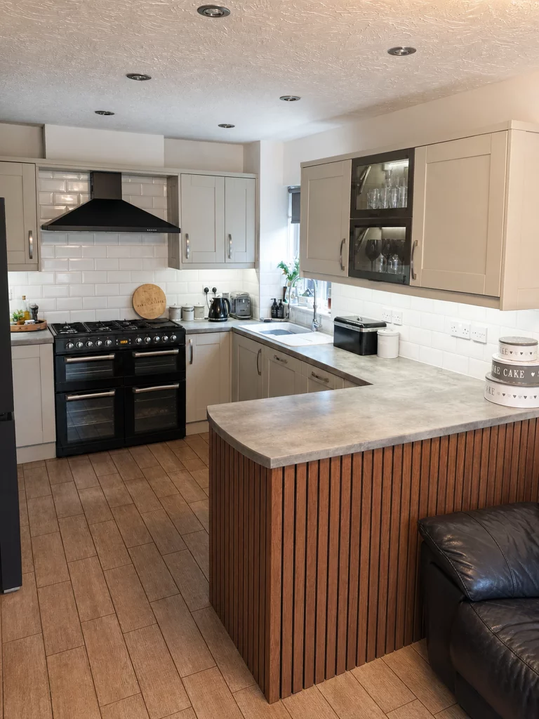 Contemporary two-tone kitchen with a curved peninsula and stone-effect worktop, wide doorway view showing the fluted curved peninsula.