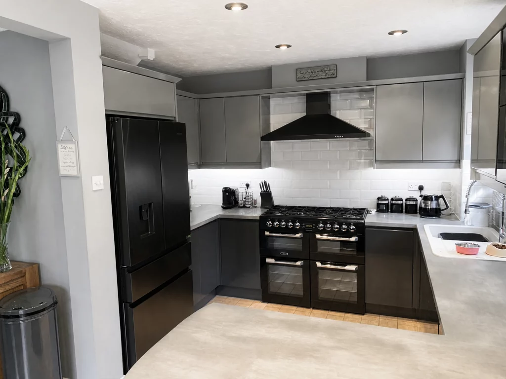 Contemporary two-tone kitchen with a curved peninsula and stone-effect worktop, front view of the range cooker and tall refrigeration.