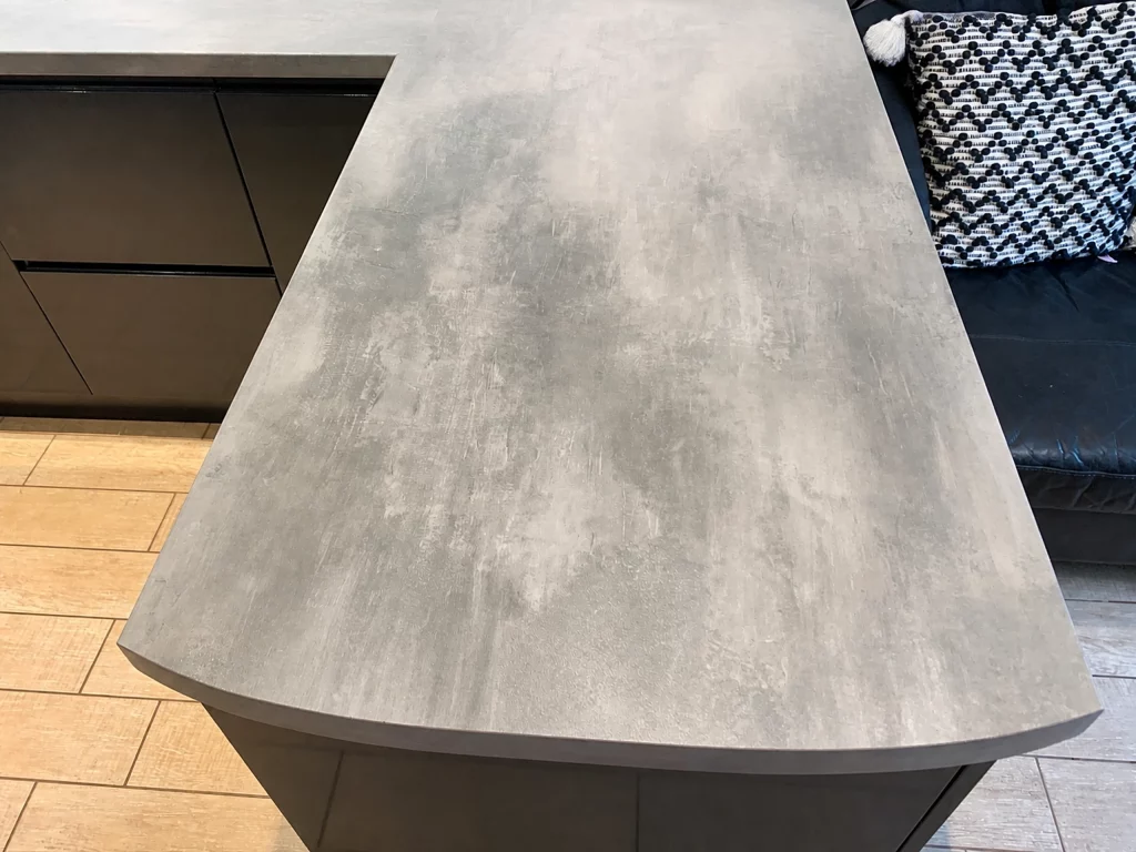 Contemporary two-tone kitchen with a curved peninsula and stone-effect worktop, close overhead view of the curved stone-effect worktop.