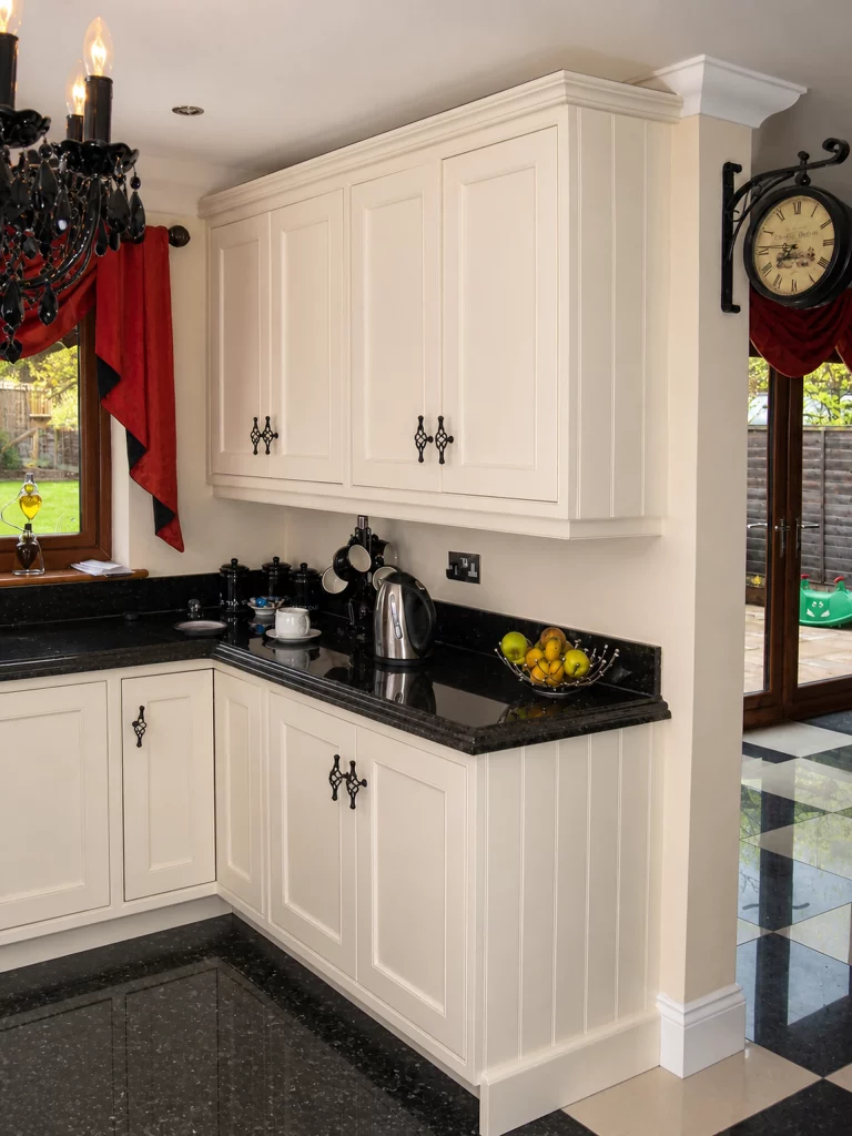 White painted Shaker kitchen with Star Galaxy granite and a central island in Wickham Bishops, painted peninsula return and tall storage.